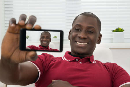 Close-up Of Young African Man Taking Selfie On Cellphone