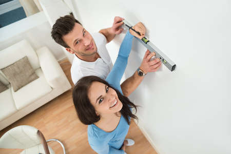 Happy Couple Marking With Pencil On Wall With Level In Houseの写真素材