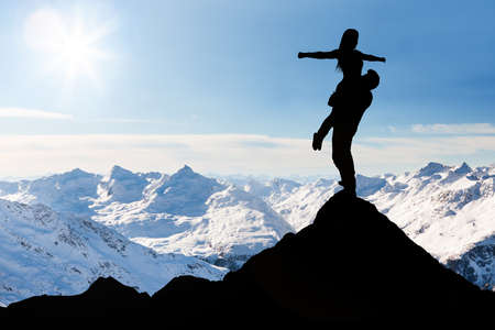 Silhouette Of Man Carrying Her Girlfriend Standing On The Top Of Snow Mountainの写真素材