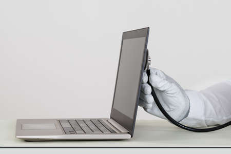 Close-up Of Person Hands In White Glove Checking Laptop With Stethoscopeの写真素材