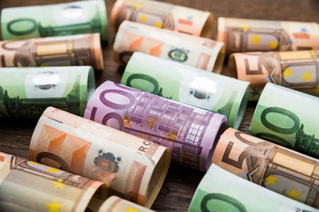 Close-up Of A Rolled Euro Banknotes On Wooden Deskの写真素材