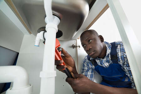 Young African Handyman Repairing Sink Pipe With Worktoolの写真素材