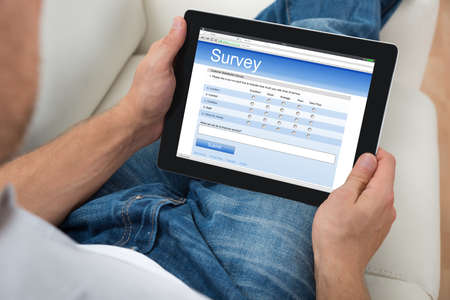 Close-up Of Person On Sofa With Digital Tablet Showing Survey Form