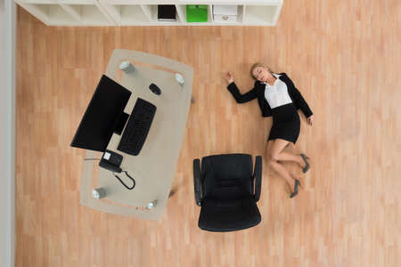 High Angle View Of Young Businesswoman Fainted On Floor In Officeの写真素材