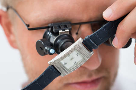 Close-up Of Young Man Looking Wrist Watch With Loupeの写真素材