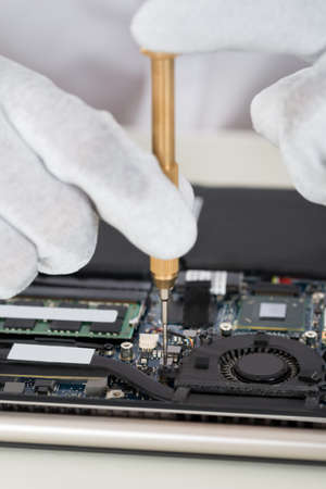 Close-up Of Person Hands In Glove Repairing Laptop Motherboardの写真素材