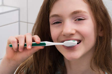 Close-up Of Cute Girl Brushing Teeth With Toothbrushの写真素材