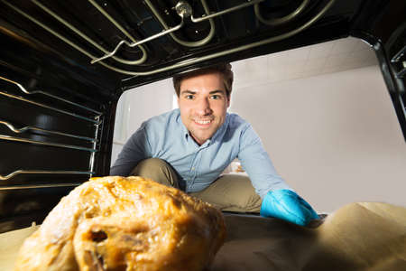 Young Happy Man Looking At Chicken View From Inside The Oven