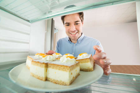 Portrait Of Young Handsome Man Taking Cake View From Inside The Refrigeratorの写真素材