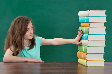 Portrait Of Girl Touching Multi-colored Stack Of Books At The Tableの写真素材