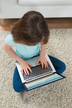 High Angle View Of Girl Looking At Video On Laptop At Home