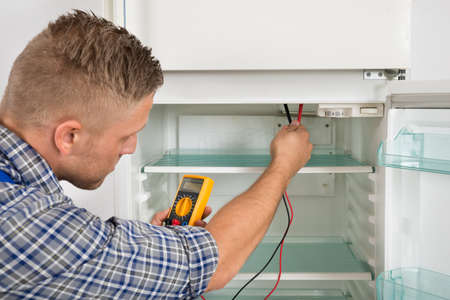 Young Male Technician Checking Fridge With Digital Multimeterの写真素材