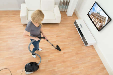 Young Woman Cleaning Floor With Vacuum Cleaner At Homeの写真素材