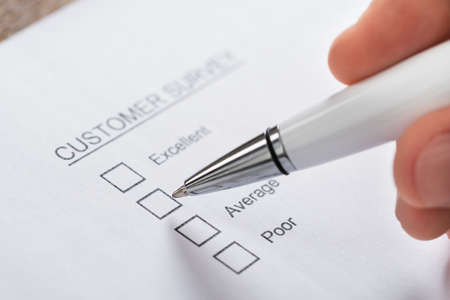 Close-up Of Person Hands With Pen Filling Customer Survey Blank Form
