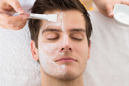 Therapist Hands With Brush Applying Face Mask To A Young Man In A Spa