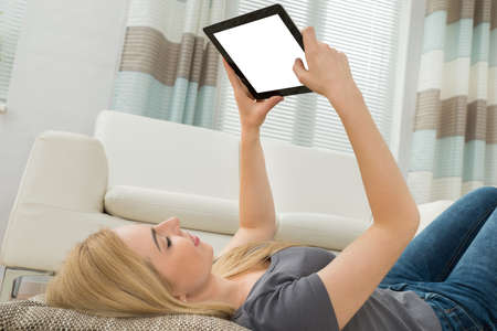 Young Woman Lying Down With Blank Screen Digital Tablet
