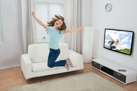 Cute Excited Girl Jumping In Living Roomの写真素材