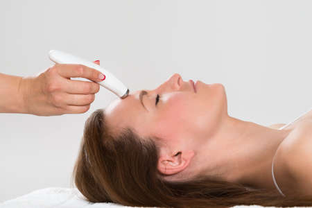 Young Woman Receiving Microdermabrasion Therapy In Beauty Clinic