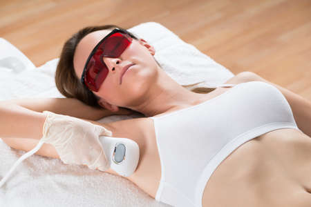 Beautician Removing Hair Of Young Woman's Armpit With Epilator