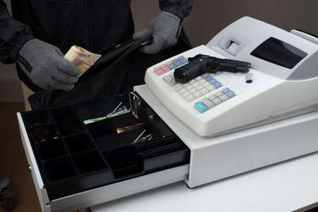 Close-up Of Robber Hands Taking Paper Money From Cash Register