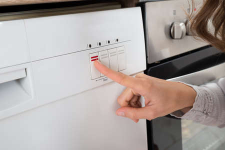 Close-up Of Person Hands Pressing Button Of Dishwasherの写真素材