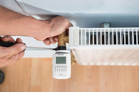 Close-up Photo Of Technician Installing Digital Thermostat Using Screwdriver