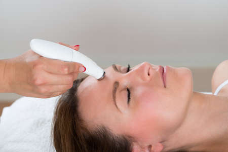 Young Woman Receiving Microdermabrasion Therapy In Beauty Clinic