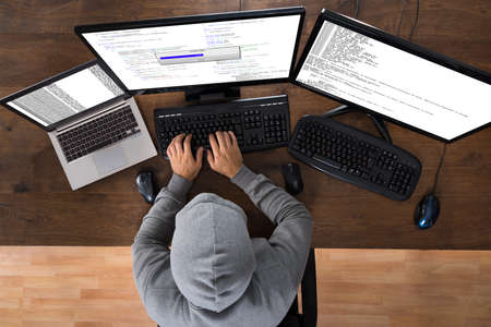 High Angle View Of Hacker Stealing Information From Computers At Desk