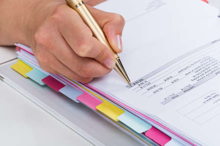 Close-up Of Person Hands With Pen Over Invoice Paper
