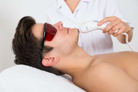 Young Man Receiving Laser Hair Removal Treatment At Beauty Centerの写真素材