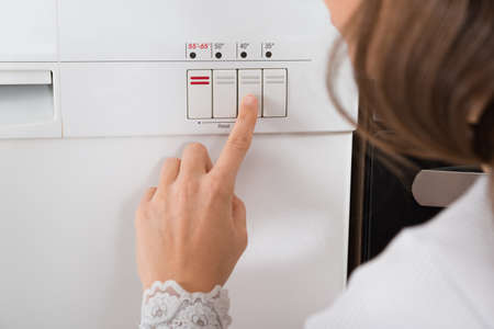 Close-up Of Person Hands Pressing Button Of Dishwasherの写真素材