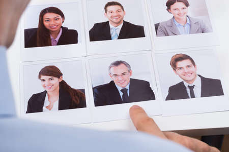 Close-up Of Businessperson Choosing Photograph Of Best Job Candidateの写真素材