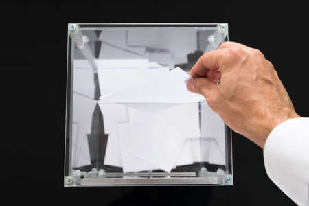 High Angle View Of Person Hands Putting Voting Ballot In A Slot Of Boxの写真素材
