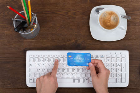 Person Hands With Credit Card Using Computer Keyboard At Deskの写真素材