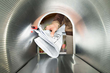 Close-up Of Postman Hands Delivering Newspaper View From Inside The Mailboxの写真素材