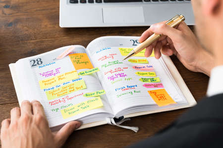 Close-up Of Businessperson Reading List Of Work In Diaryの写真素材