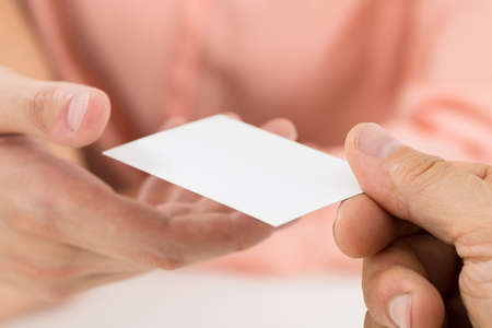 Close-up Of Person Hands Giving Blank Visiting Card To Another Personの写真素材