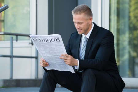 Close-up Of Businessman Sitting And Reading Newspaperの写真素材
