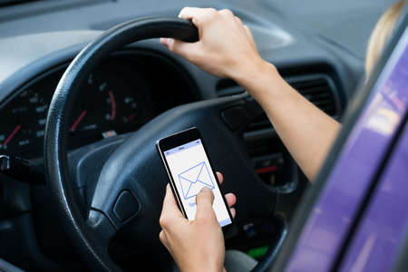 Cropped image of hands checking message while driving carの写真素材