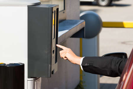 Person Sitting In Car Using Parking Machine To Pay For Parking