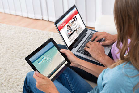 Close-up Of Couple Watching Video And News On Electronic Devices At Homeの写真素材