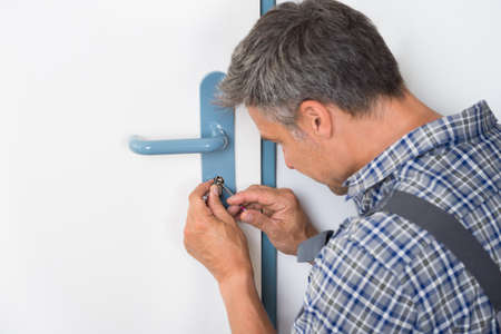 Cropped image of lockpicker fixing door handle at homeの写真素材