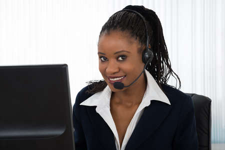 Portrait Of A Young Smiling Businesswoman Talking On Headset