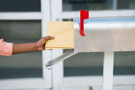 Close-up Of Person's Hand Putting Letters In Mailbox