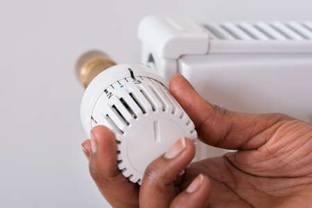 Close-up Of Person's Hand Holding Radiator Thermostatの写真素材