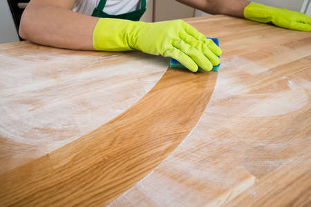 Cropped image of man cleaning dust on wooden table at home