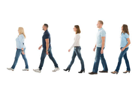 Full length side view of men and women walking in queue isolated on white backgroundの写真素材