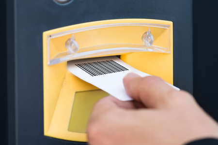Close-up Of A Person's Hand Inserting Ticket In Parking Slotの写真素材