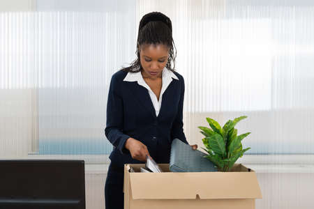 Sad African Businesswoman Carrying Box With Her Belongings In Officeの写真素材