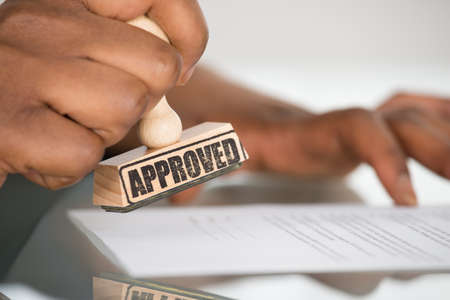 Close-up Of A Person's Hand Stamping On Approved Contract Formの写真素材